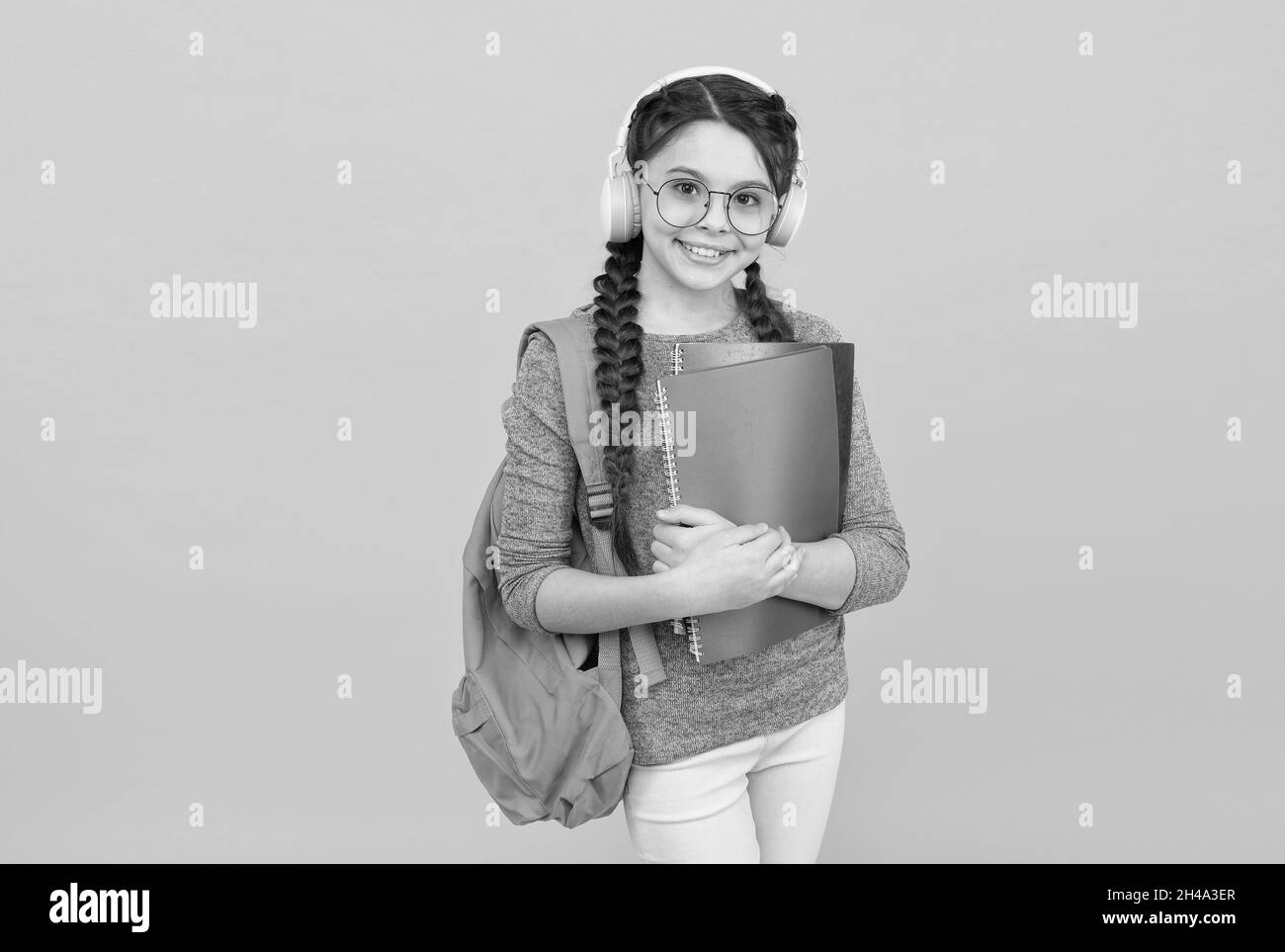 Ragazza studentesca moderna con zaino e la scuola fornisce sfondo giallo, concetto homeschooling Foto Stock