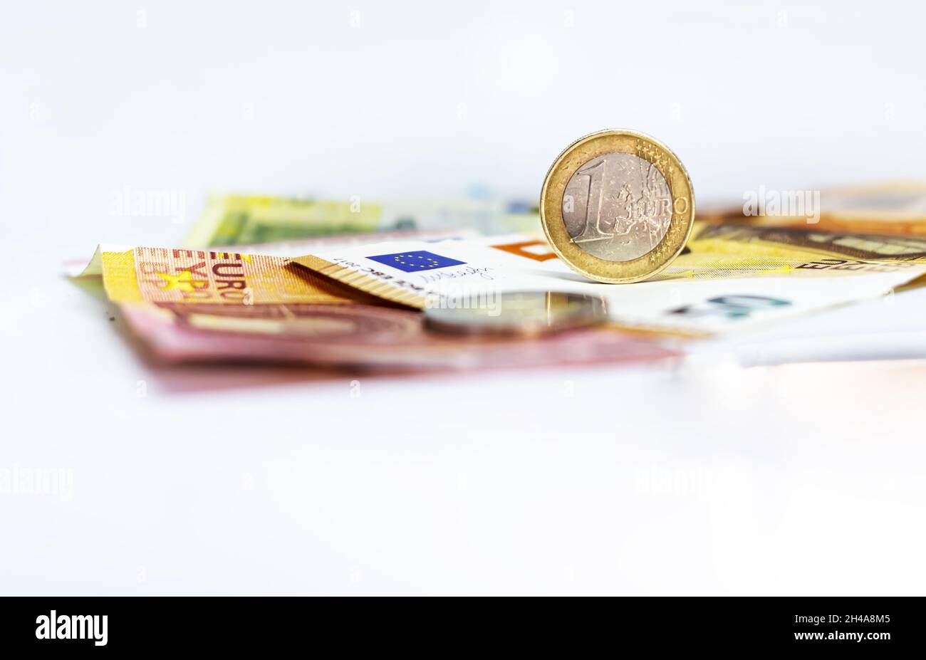 Una moneta da 1 euro usata in cima ad alcune banconote in euro. Economia e finanza nell'Unione europea. Foto Stock