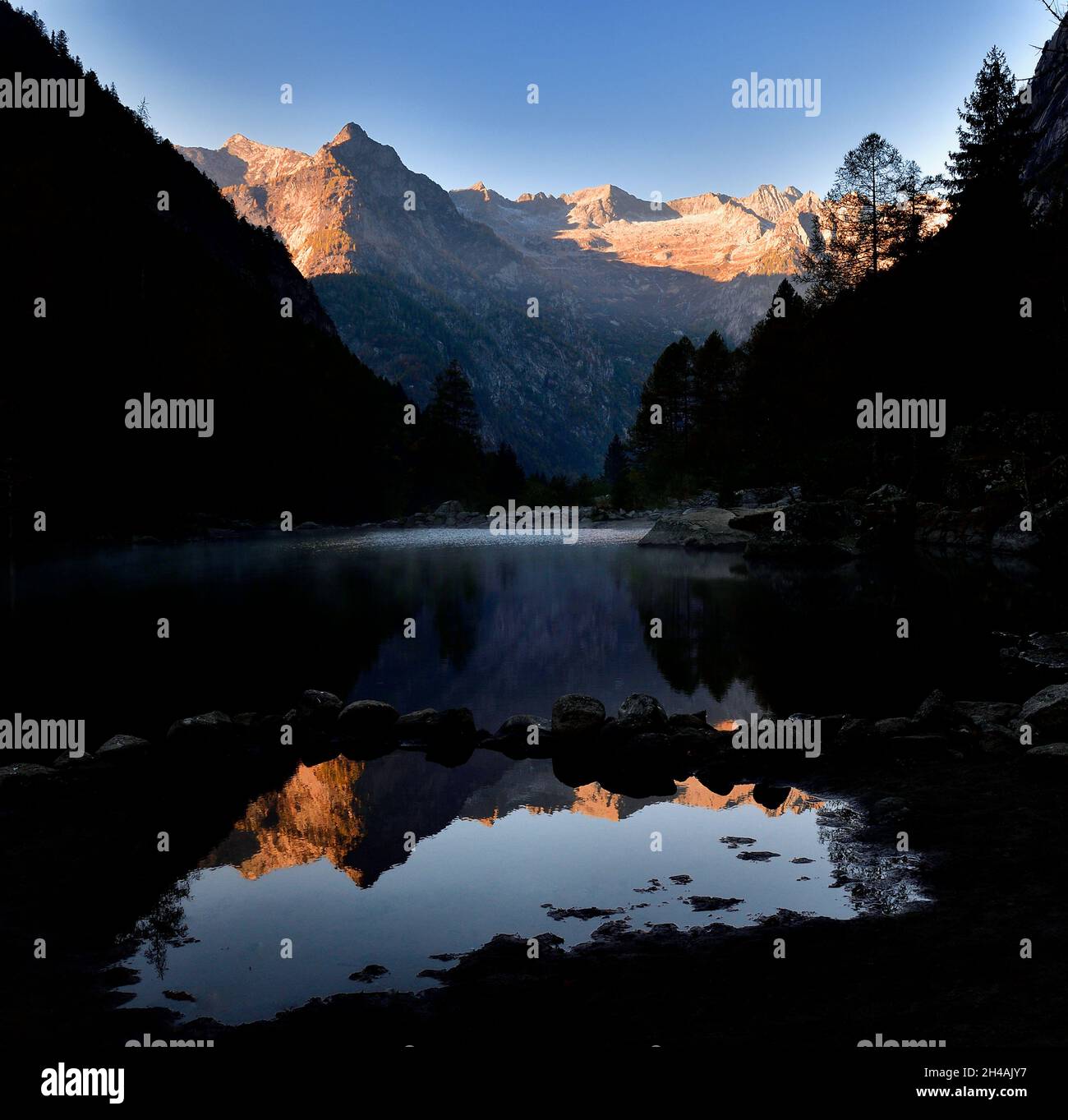 Riflesso della catena montuosa nel lago in Val di Mello in una mattinata di nebbia Foto Stock