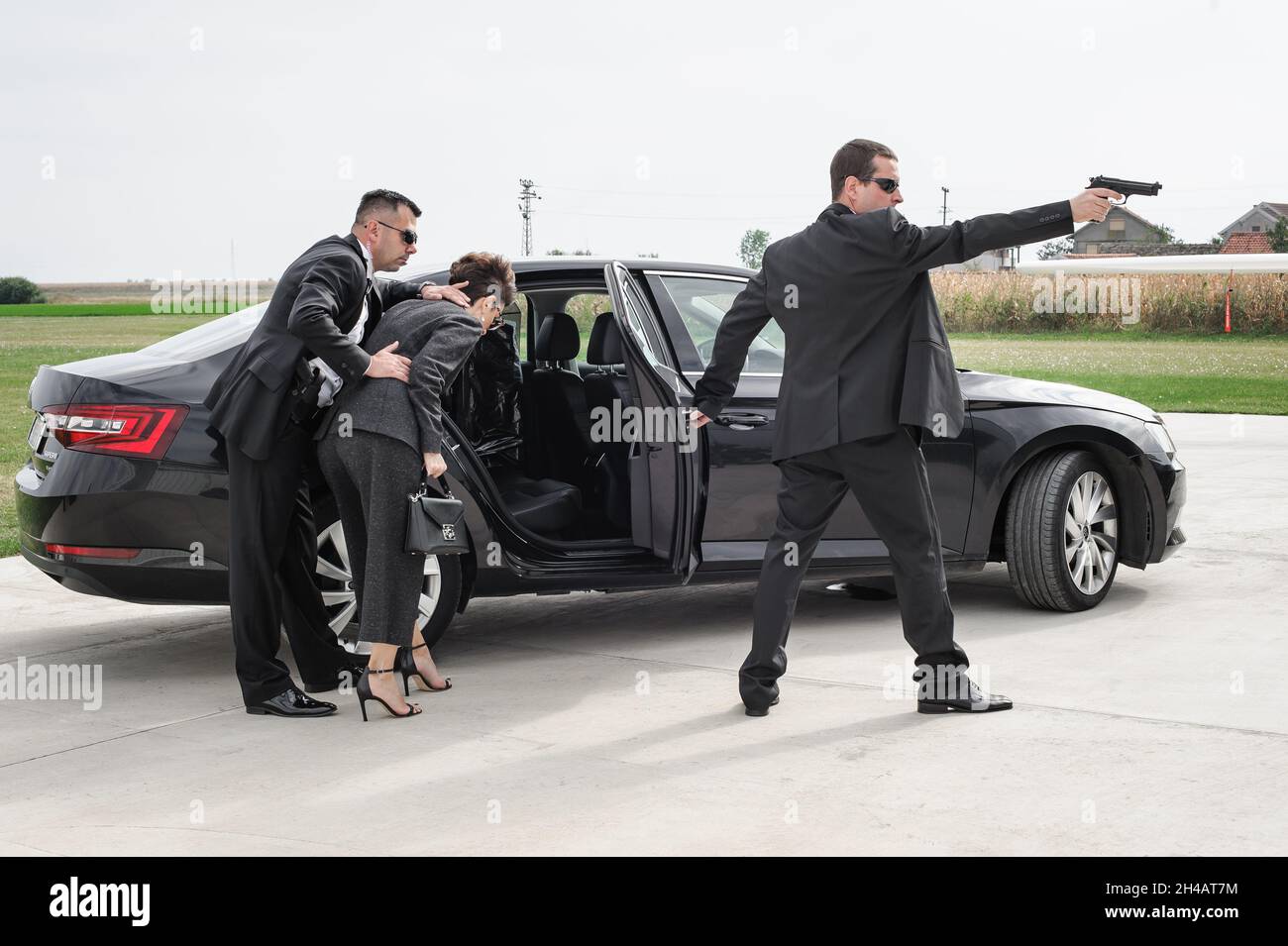 Il team armato professionale di guardie del corpo femminili e maschili protegge la persona della celebrità in limousine auto. Bodyguard e protezione personale VIP. Professate Foto Stock