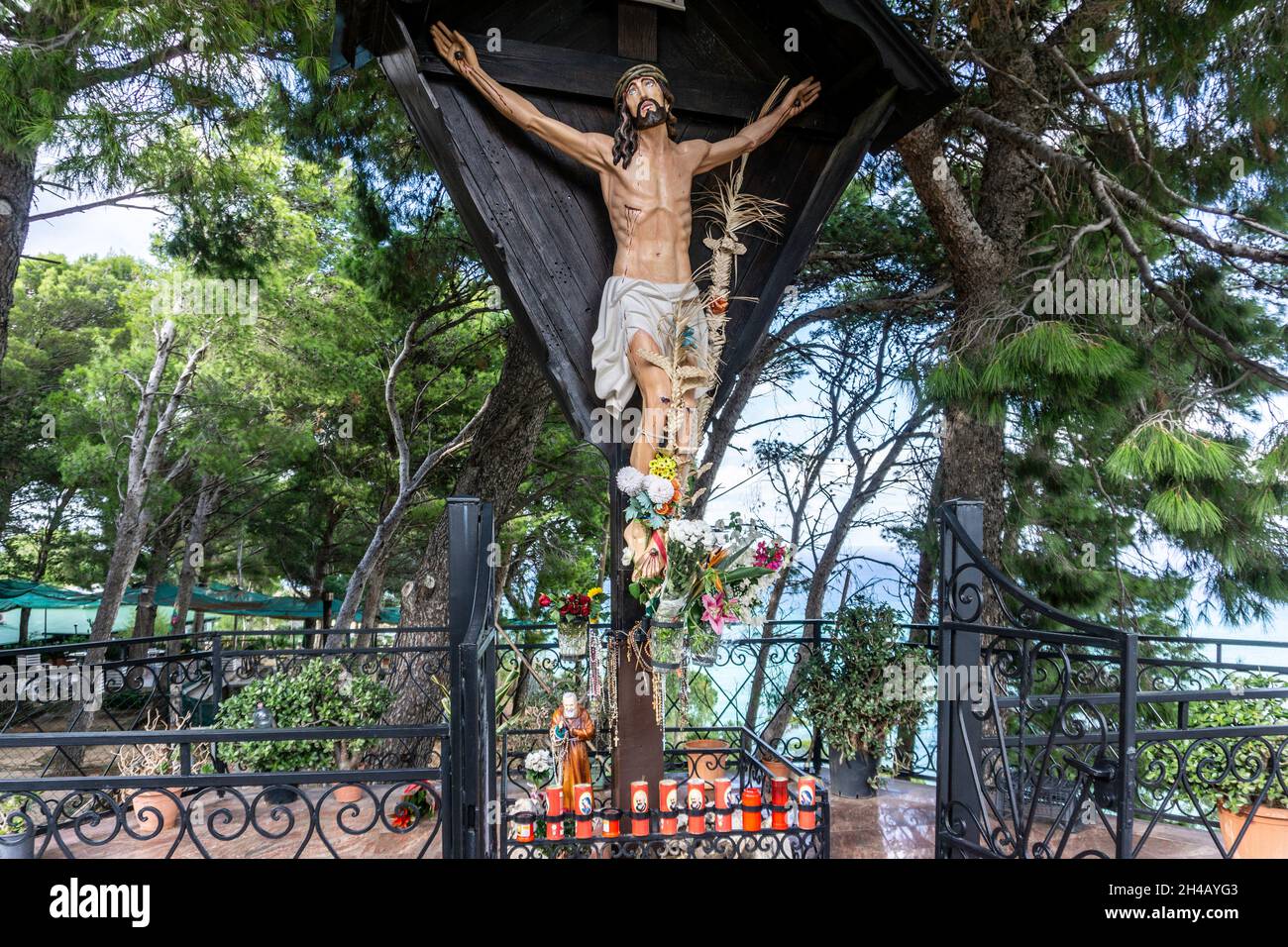 Una statua del crocifisso Gesù Cristo che domina il porto di Castellammare del Golfo in Sicilia. Foto Stock