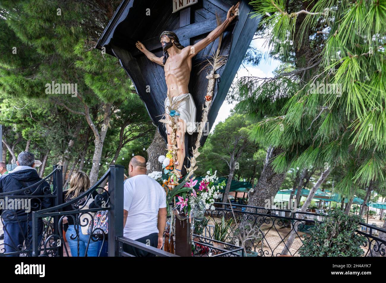 Le persone che pagano il loro rispetto alla statua del Gesù Cristo crocifisso che si affaccia sul porto di Castellammare del Golfo in Sicilia, Italia. Foto Stock
