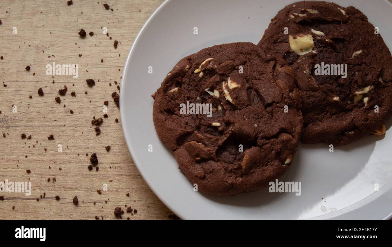 Biscotti con due gocce di cioccolato su un piatto con briciole sparse Foto Stock