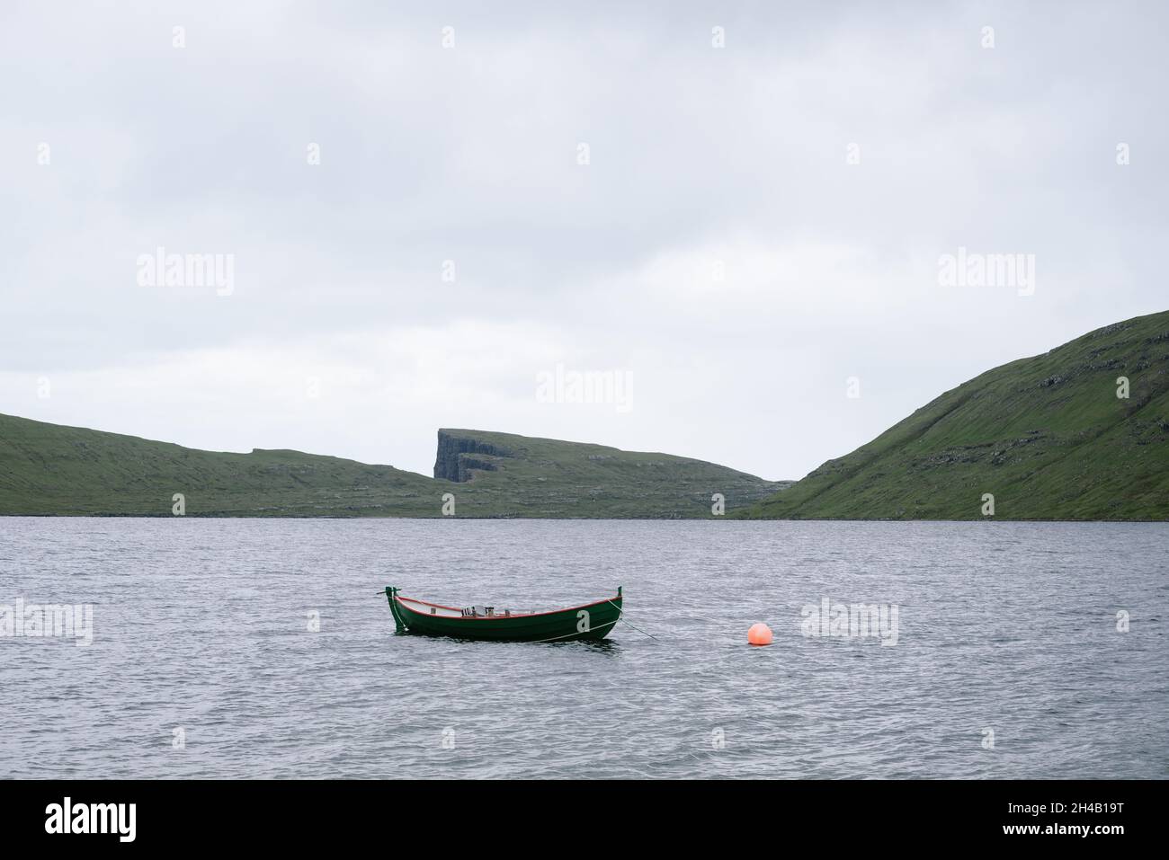 Barca sul lago Sorvagsvatn o Leitisvatn, Isole Faroe. Paesaggio del nord in tempo nuvoloso Foto Stock