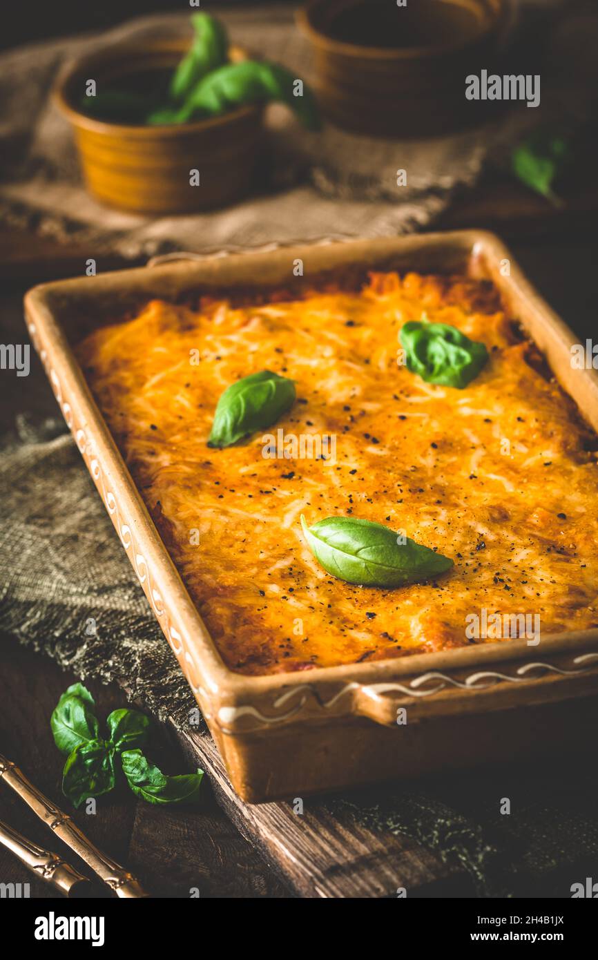 Pasta e formaggio cuocere con salsa di pomodoro e basilico su sfondo di legno, verticale Foto Stock