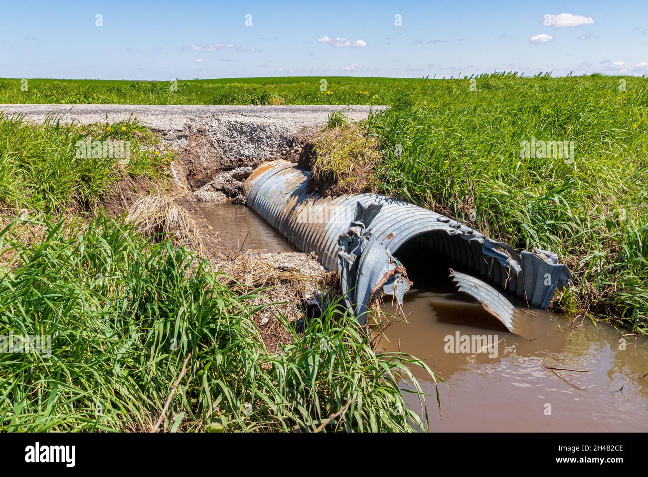 Danni alla strada e al fondo stradale causati da alluvioni e erosione dell'acqua. Concetto di riparazione stradale, infrastrutture e controllo dell'erosione Foto Stock