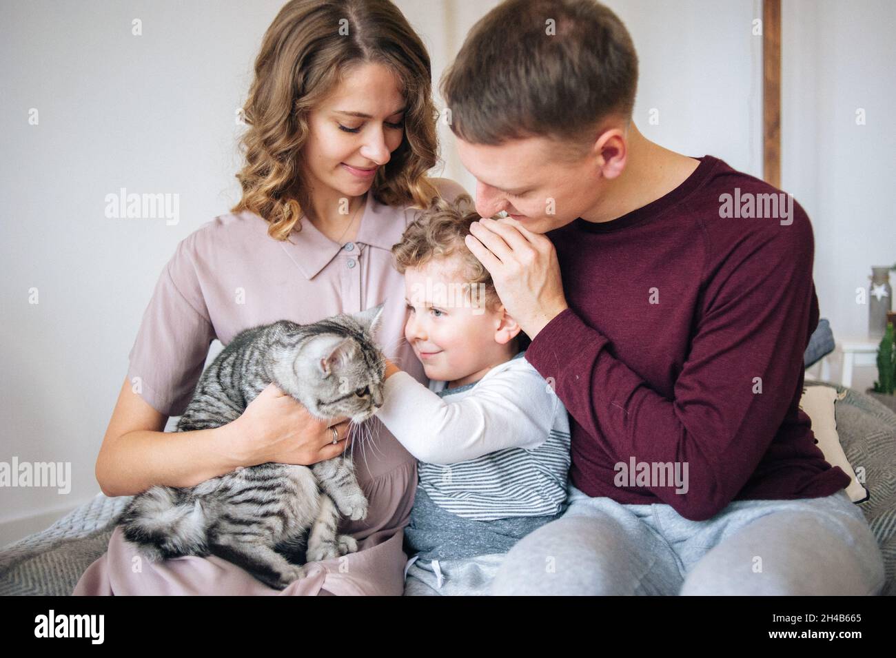 Padre e madre tengono il figlio e il gatto nelle mani. Momento di gara Foto Stock