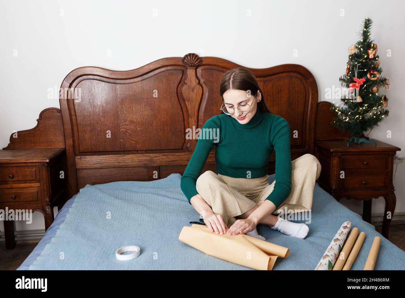 La giovane donna ha un regalo di Natale mentre si siede sul letto a casa Foto Stock