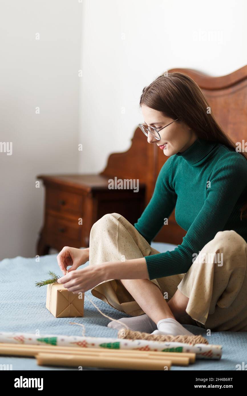 una giovane donna regala un regalo di natale seduto sul letto di casa Foto Stock