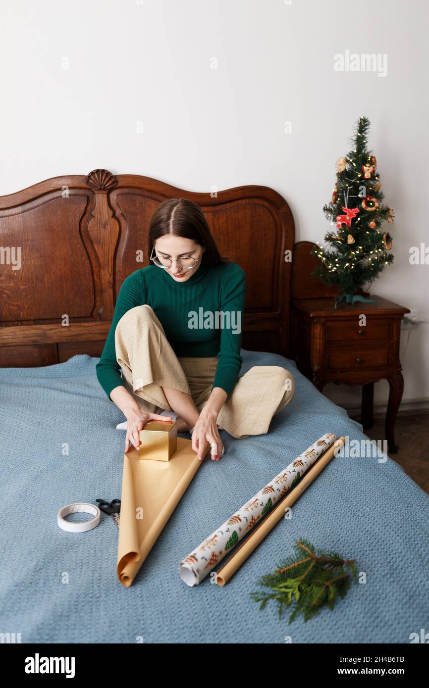 una giovane donna regala un regalo di natale seduto sul letto di casa Foto Stock