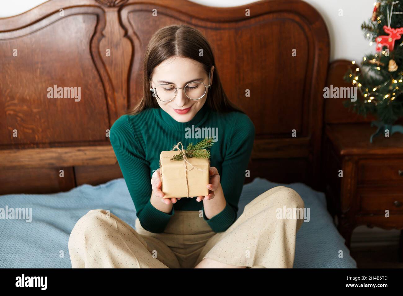 Giovane donna con un regalo natalizio seduto sul letto Foto Stock