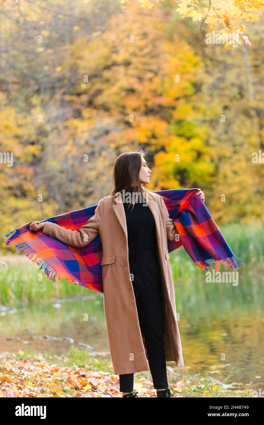 Giovane ragazza bruna godendo camminare nel parco avvolto in plaid Foto Stock