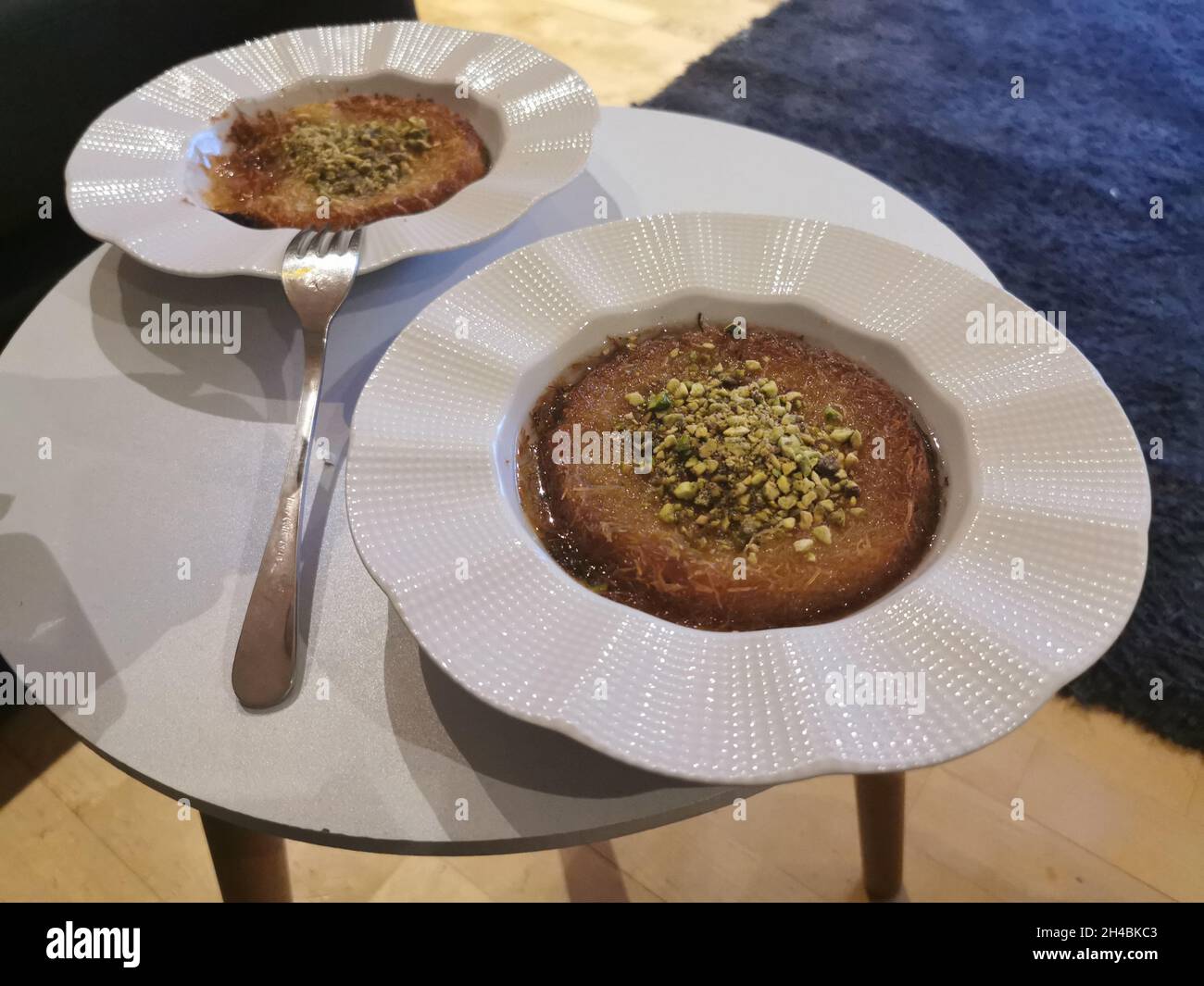 Kunafa in un'enorme lastra di ceramica bianca. Dessert turco gustoso e gustoso Foto Stock