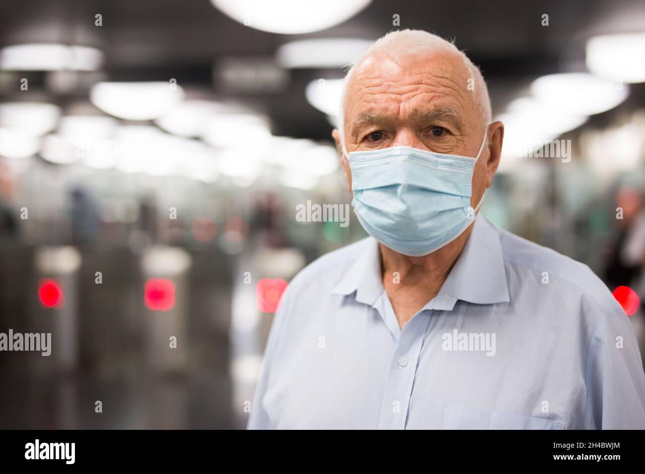 Uomo vecchio in maschera all'ingresso della stazione della metropolitana Foto Stock