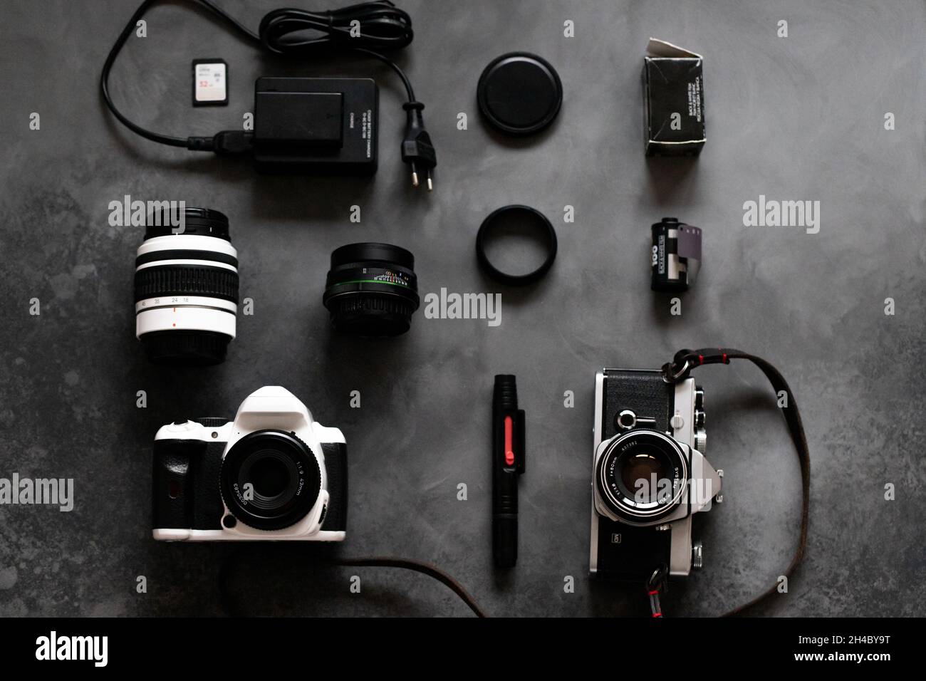Fotocamere digitali e per film, obiettivi, film, caricabatterie, scheda di memoria, detergente per lenti, coperchio. Foto su sfondo grigio neutro. Disposizione piatta. Spazio di copia. Foto Stock