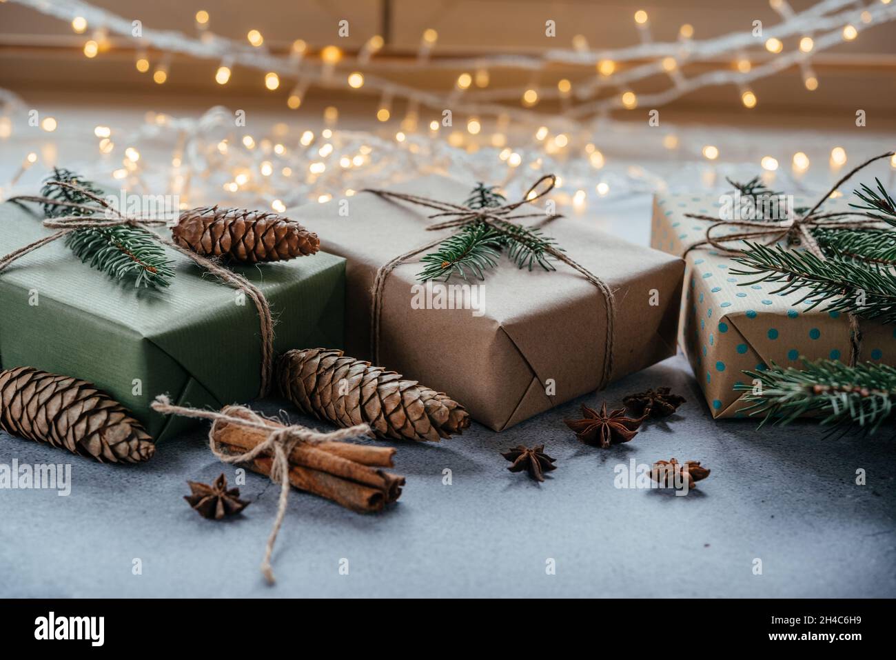 Scatole regalo di Natale senza rifiuti confezionati in carta kraft con coni di pino, legno eco decor e luci di Natale Foto Stock