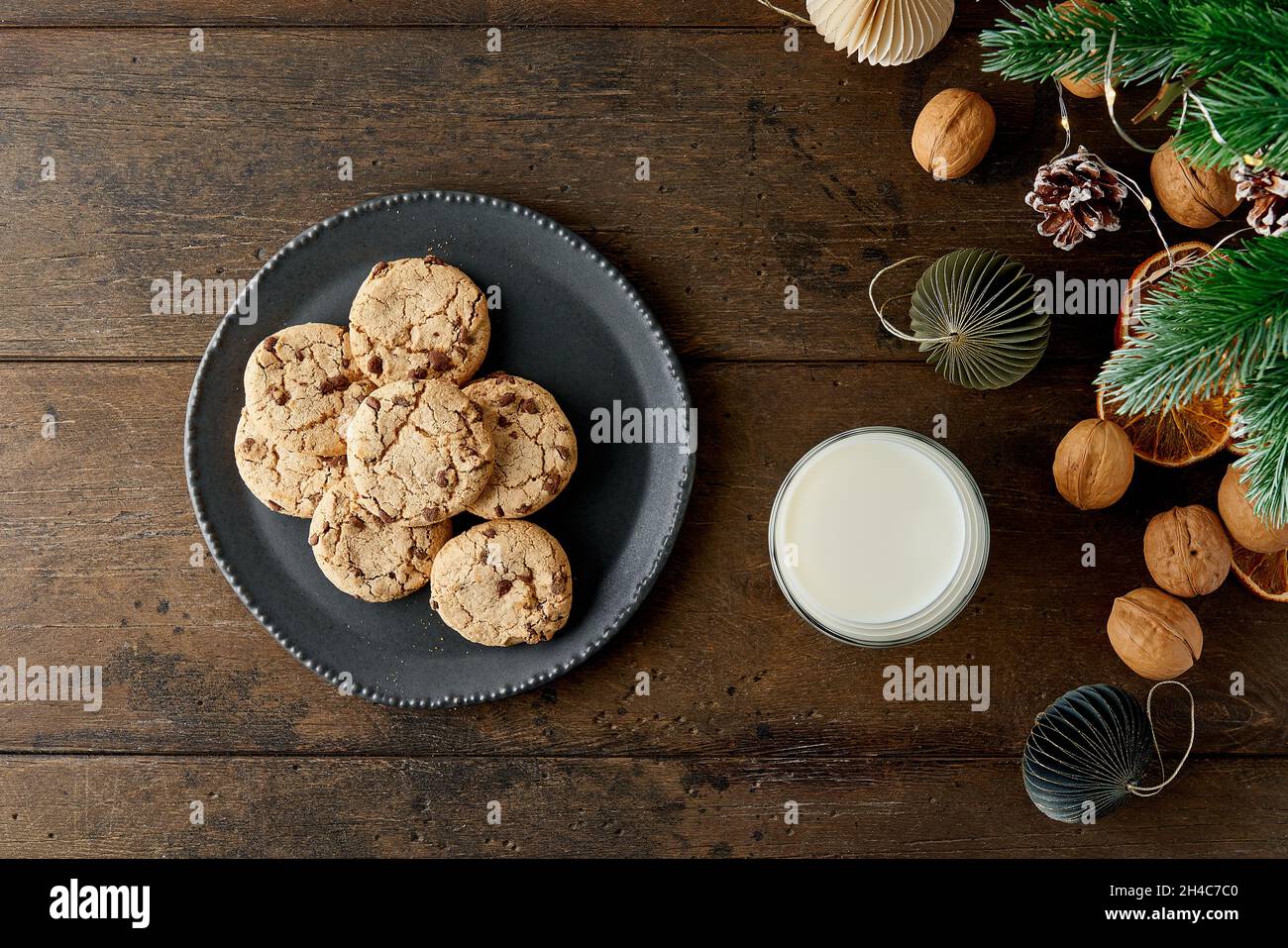 Bicchiere di latte e piatto di biscotti con cioccolato croccante su sfondo decorato a natale Foto Stock