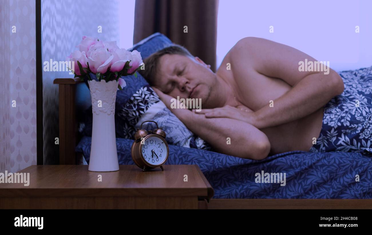 L'uomo si addormenta rapidamente nel letto dell'appartamento e non sente la sveglia. Foto Stock