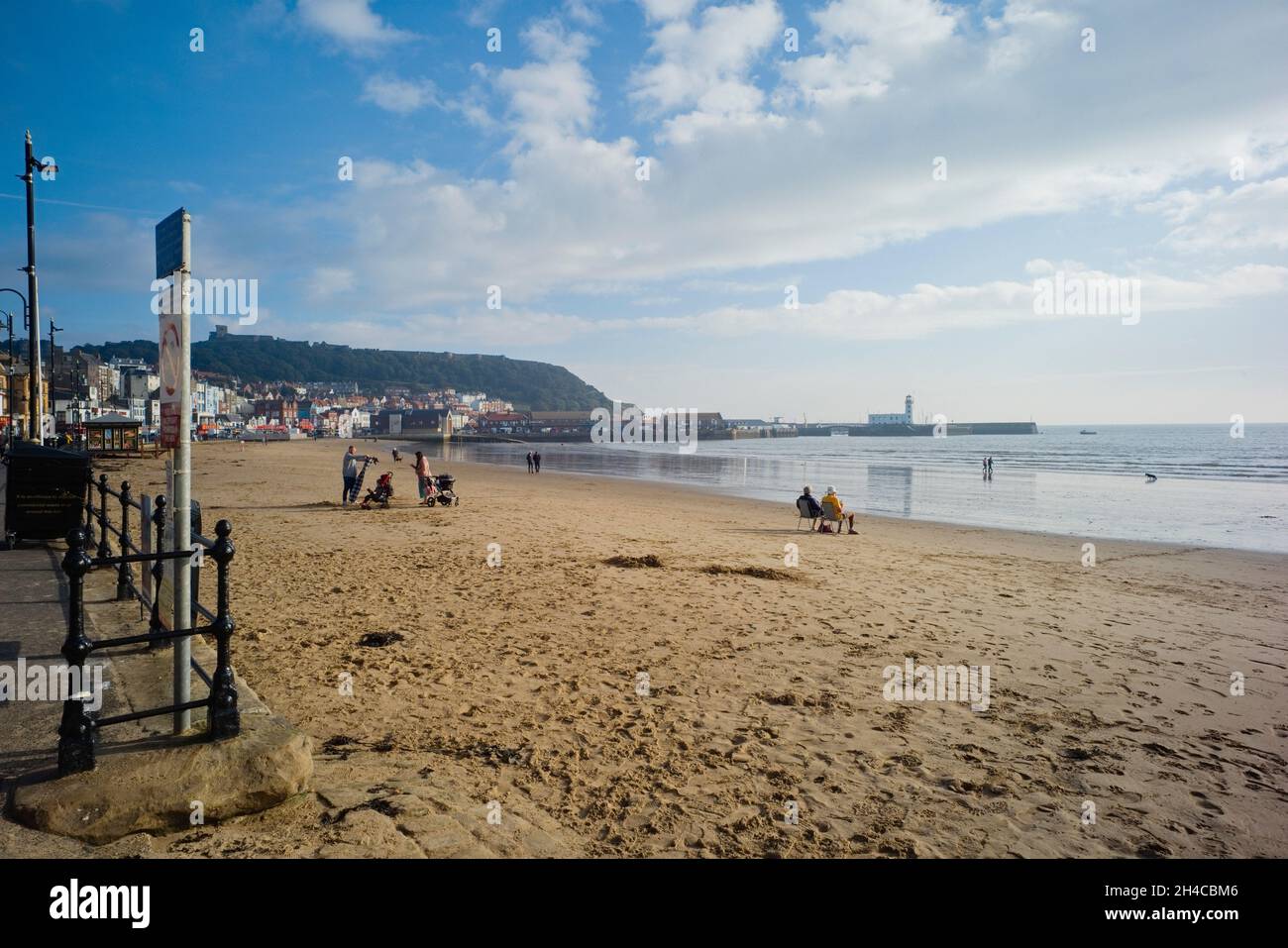 Spiaggia di Scarborough con persone anziane che si siedono al mattino presto Foto Stock