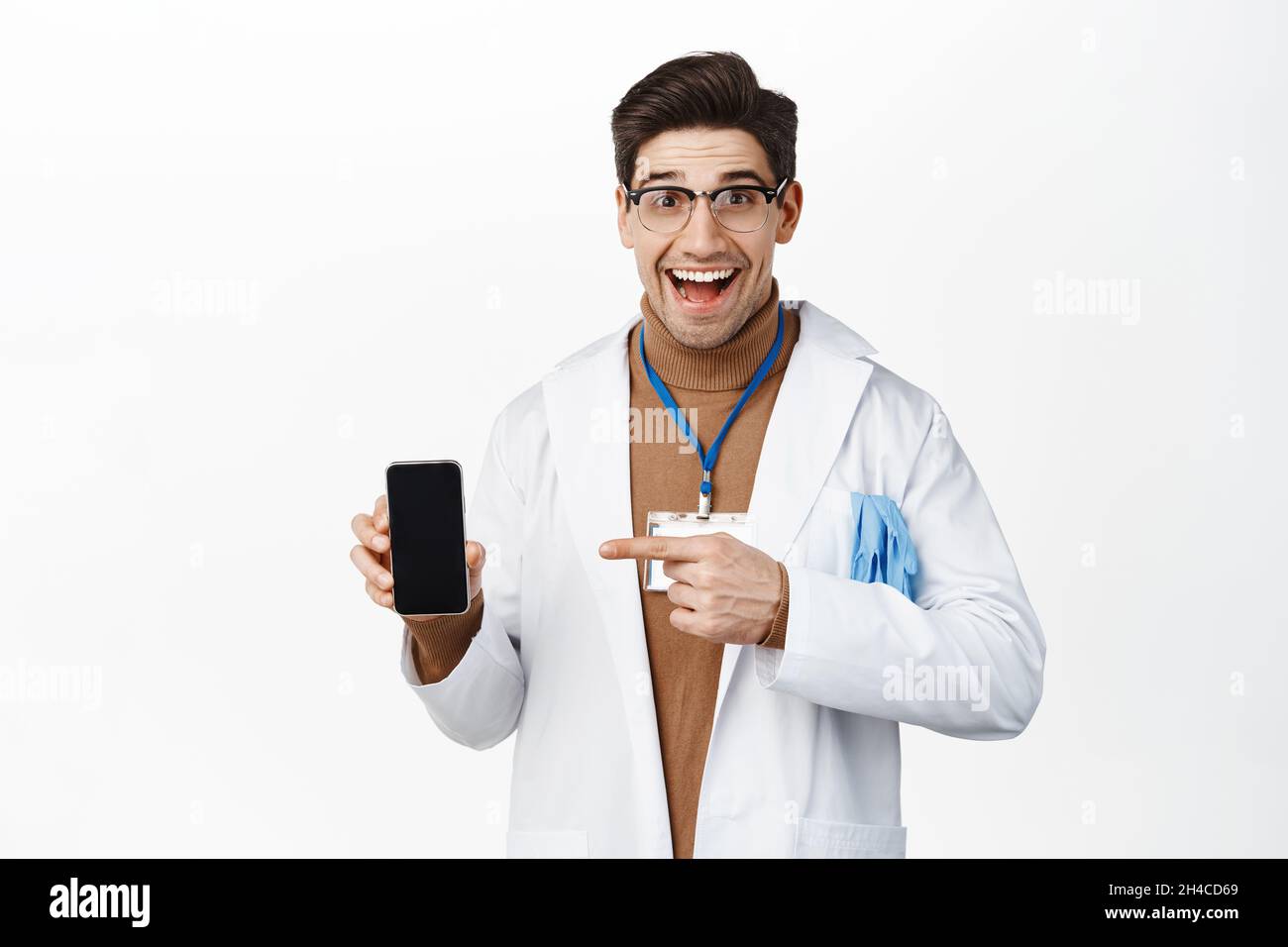 Medico sorridente in occhiali e uniforme clinica, puntando il dito sullo  schermo dello smartphone, mostrando l'app medica del telefono cellulare, in  piedi su sfondo bianco Foto stock - Alamy