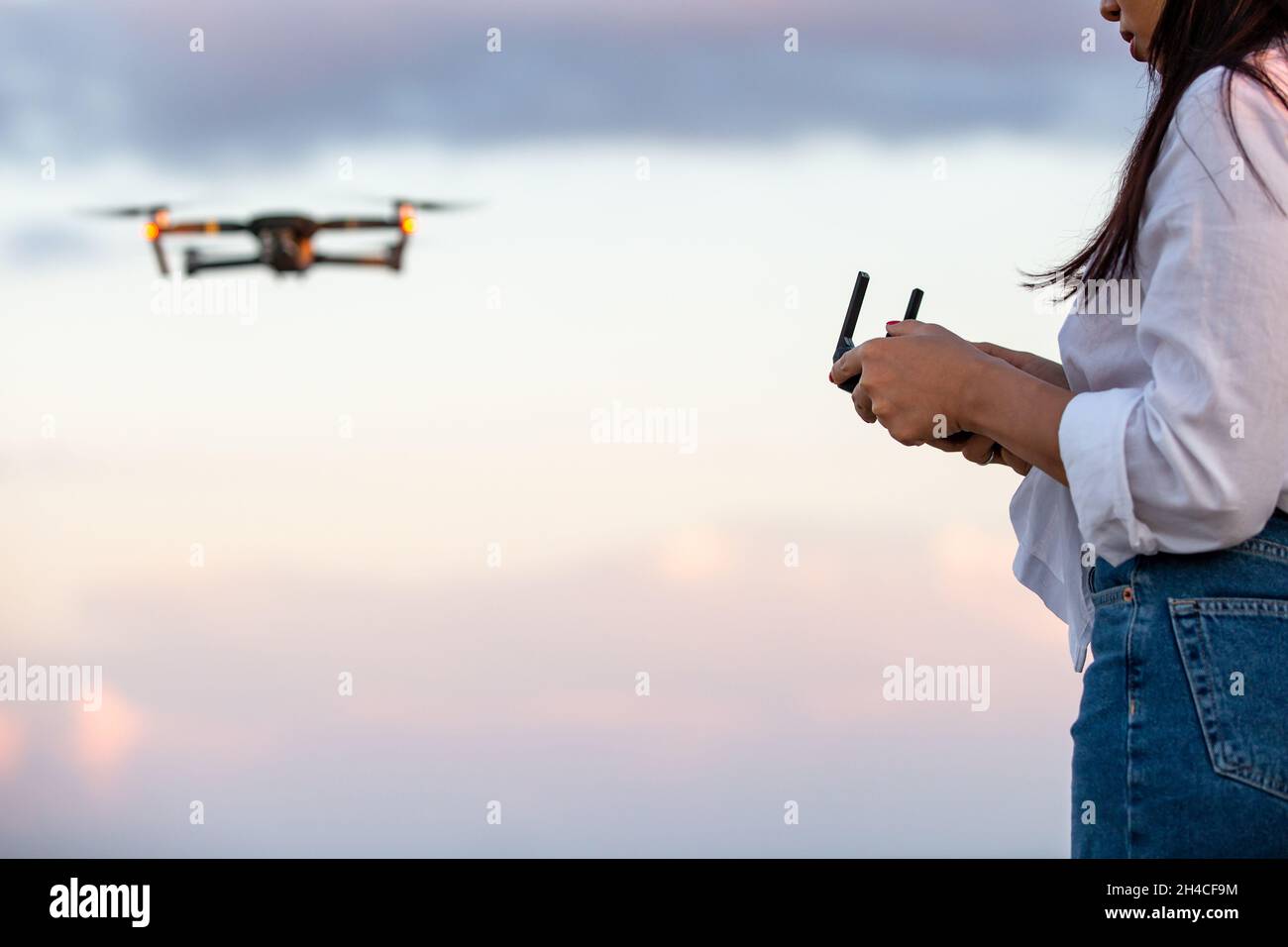 Una giovane donna che opera un drone UAV Foto Stock