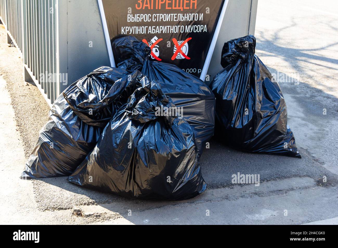 Grandi sacchi neri di rifiuti vicino al dumpster (iscrizione in russo - IL  RILASCIO DI COSTRUZIONE E DI RIFIUTI DI GRANDI DIMENSIONI È PROIBITO Foto  stock - Alamy