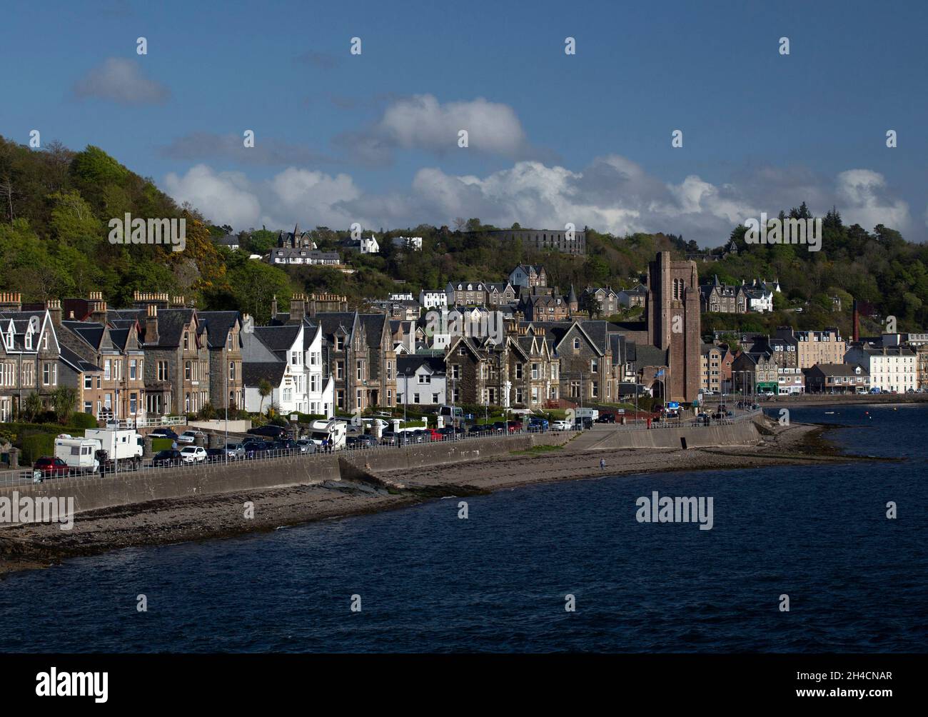Una vista lungo la costa a Oban, Scozia, con la Cattedrale di St Columba e la Torre McCaig Foto Stock