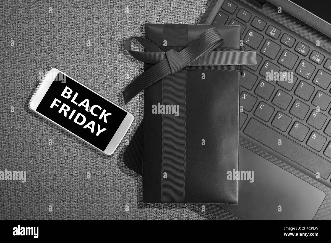Messaggio del venerdì nero sullo schermo del telefono cellulare con confezione regalo su sfondo nero. Concetto di Black Friday Foto Stock