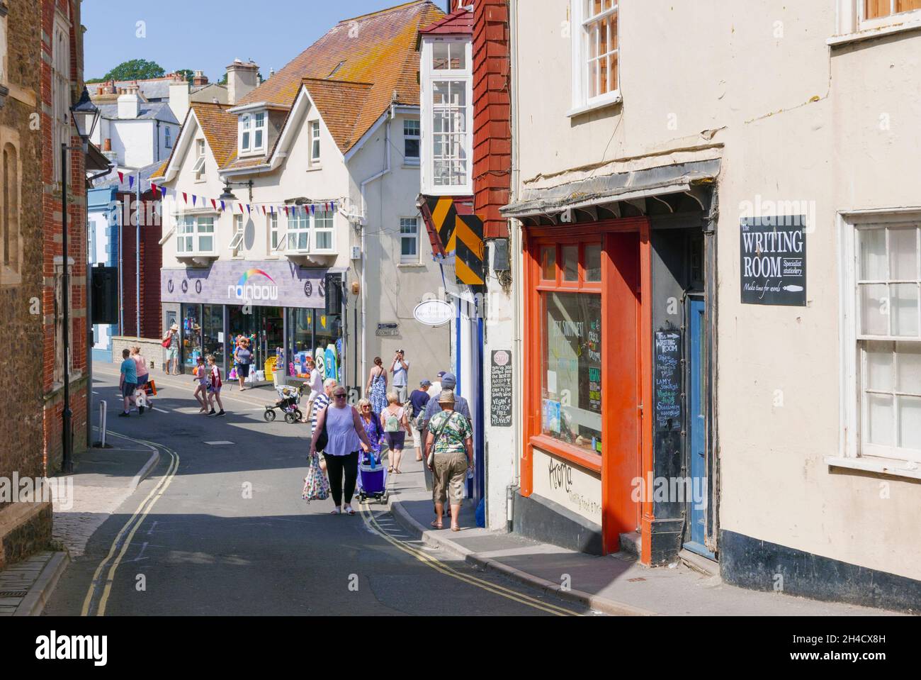 Persone che trasportano lo shopping e camminare lungo Bridge Street Centro Città Lyme Regis Dorset Inghilterra GB Europa Foto Stock