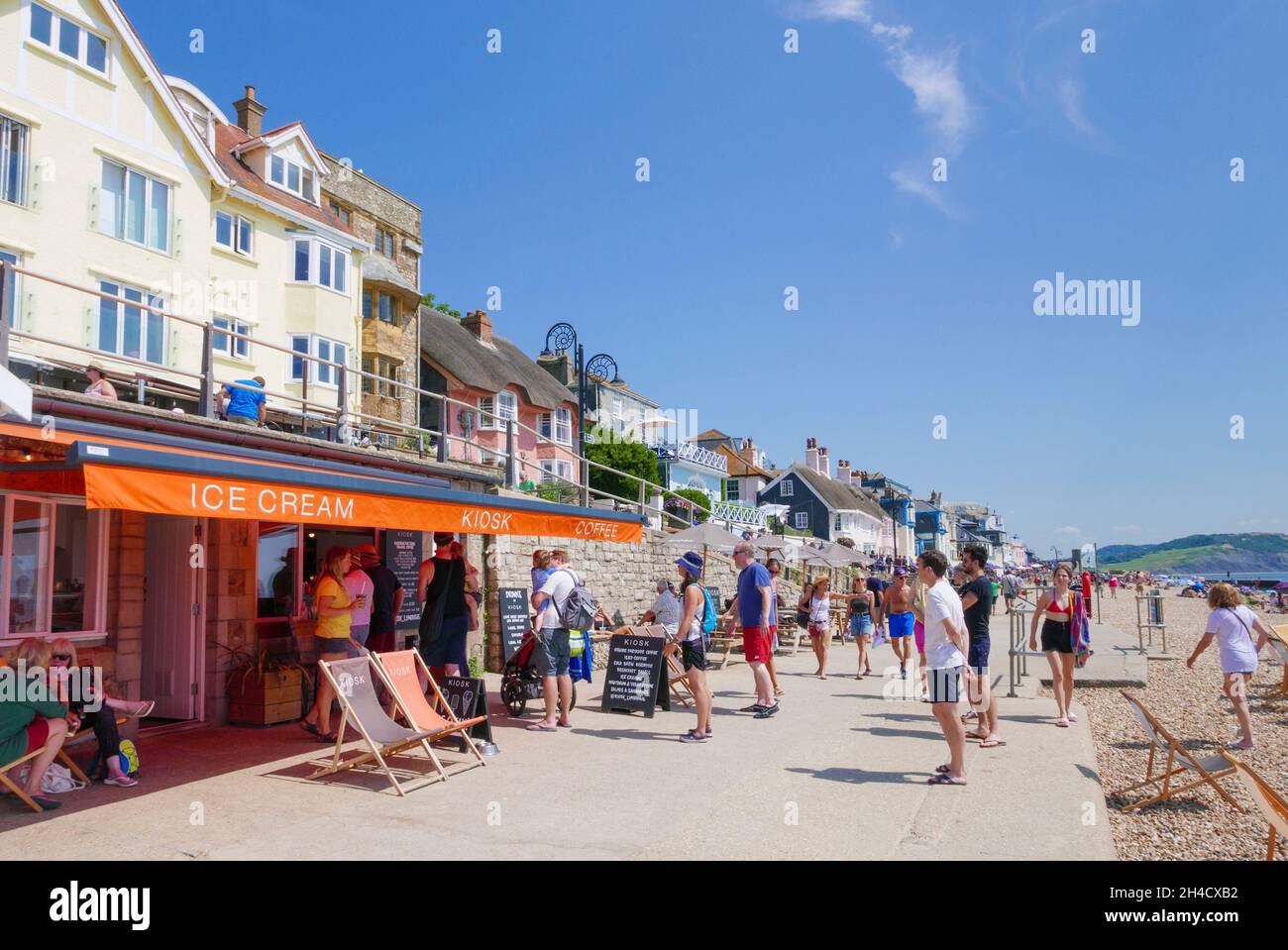Persone che si accodano per gelato in un chiosco gelato caffè sul lungomare Marine Parade con vista sulla spiaggia di sabbia a Lyme Regis Dorset Inghilterra GB Europa Foto Stock