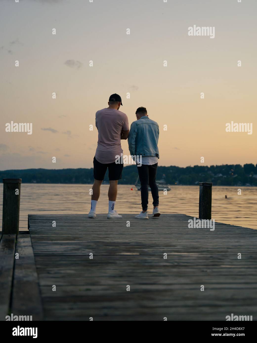 Starnberg, Germania . 23 giugno 2021. Zwei junge Männer stehen auf dem Großen Steg von Percha. Im Hintergrund sieht man das Ufer von Starnberg im Sonnenuntergang. * due giovani sono in piedi sul grande molo di Percha. Sullo sfondo si può vedere la riva di Starnberg al tramonto. (Foto di Alexander Pohl/Sipa USA) Credit: Sipa USA/Alamy Live News Foto Stock