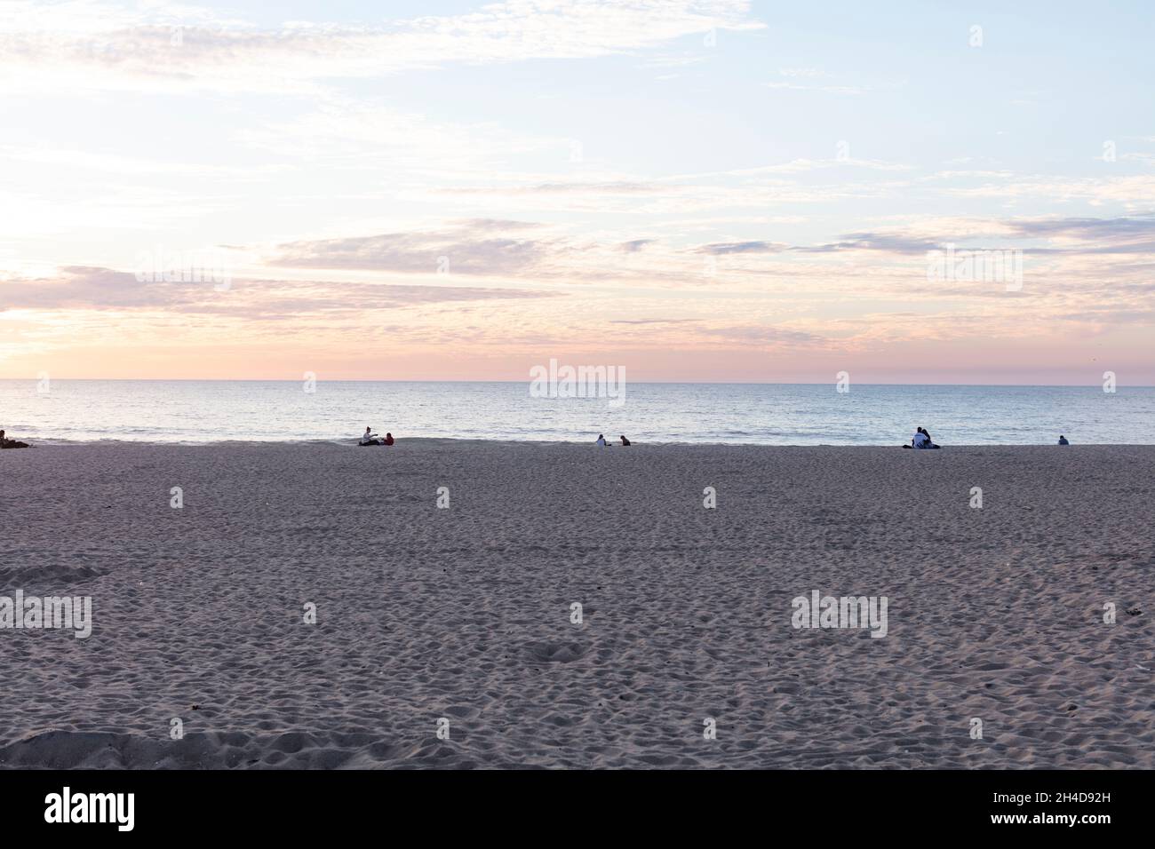 Sonnenuntergang am Strand von Espinho. Paare sitzen am Strand, nicht zu erkennen und schauen sich den Sonnenuntergang an Foto Stock