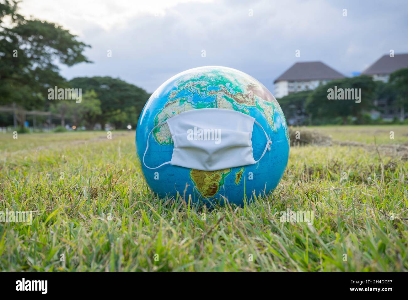 Corona virus Concept, Terra con maschera di protezione sul verde erba. Foto Stock