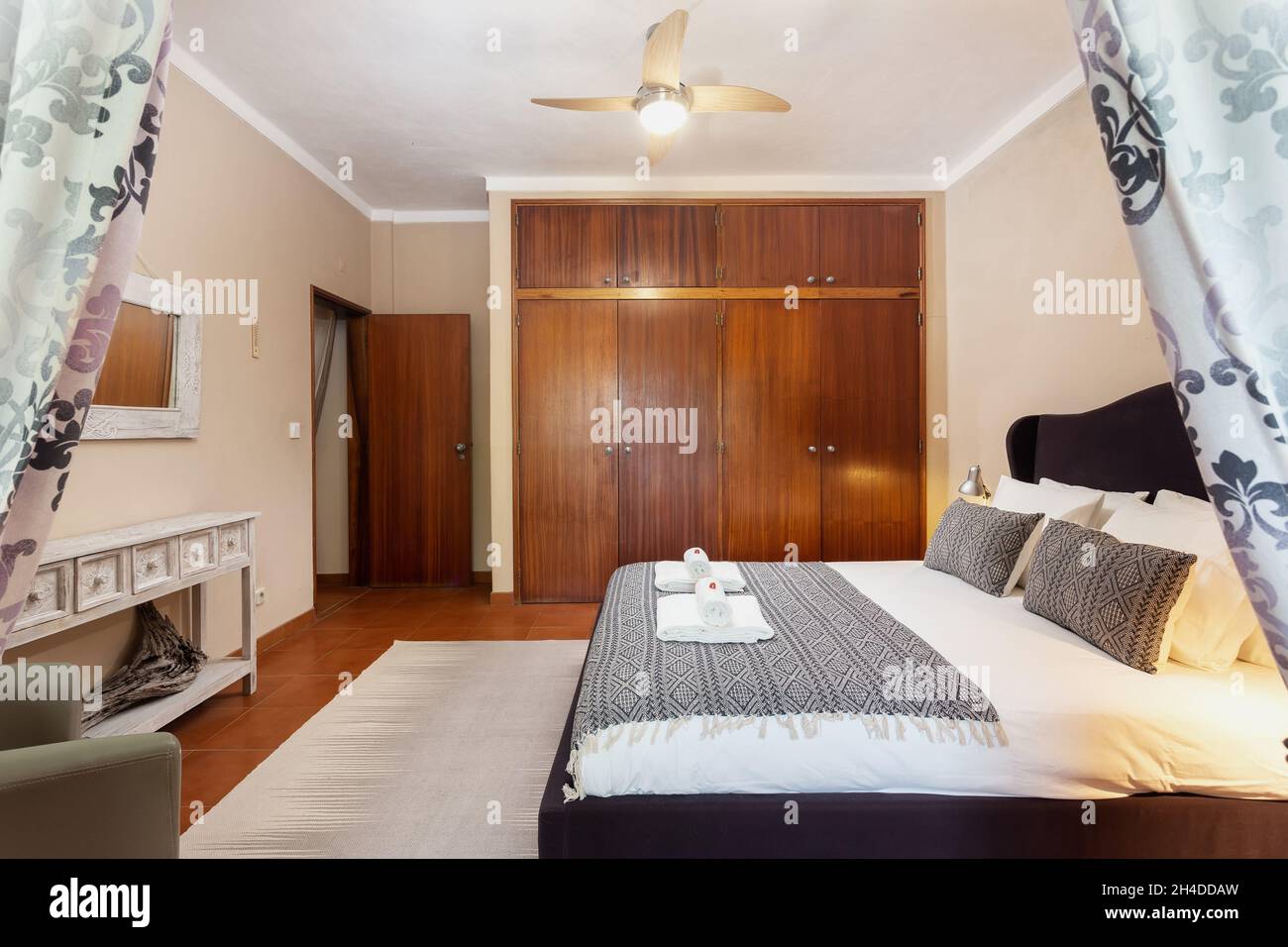 Camera da letto in classico stile mediterraneo tradizionale con letto matrimoniale. Con uno specchio e asciugamani con dolci sul letto. Foto Stock