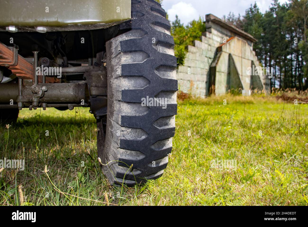 La ruota anteriore di un'auto fuoristrada con lo sfondo dell'hangar all'ex aeroporto dell'esercito Foto Stock