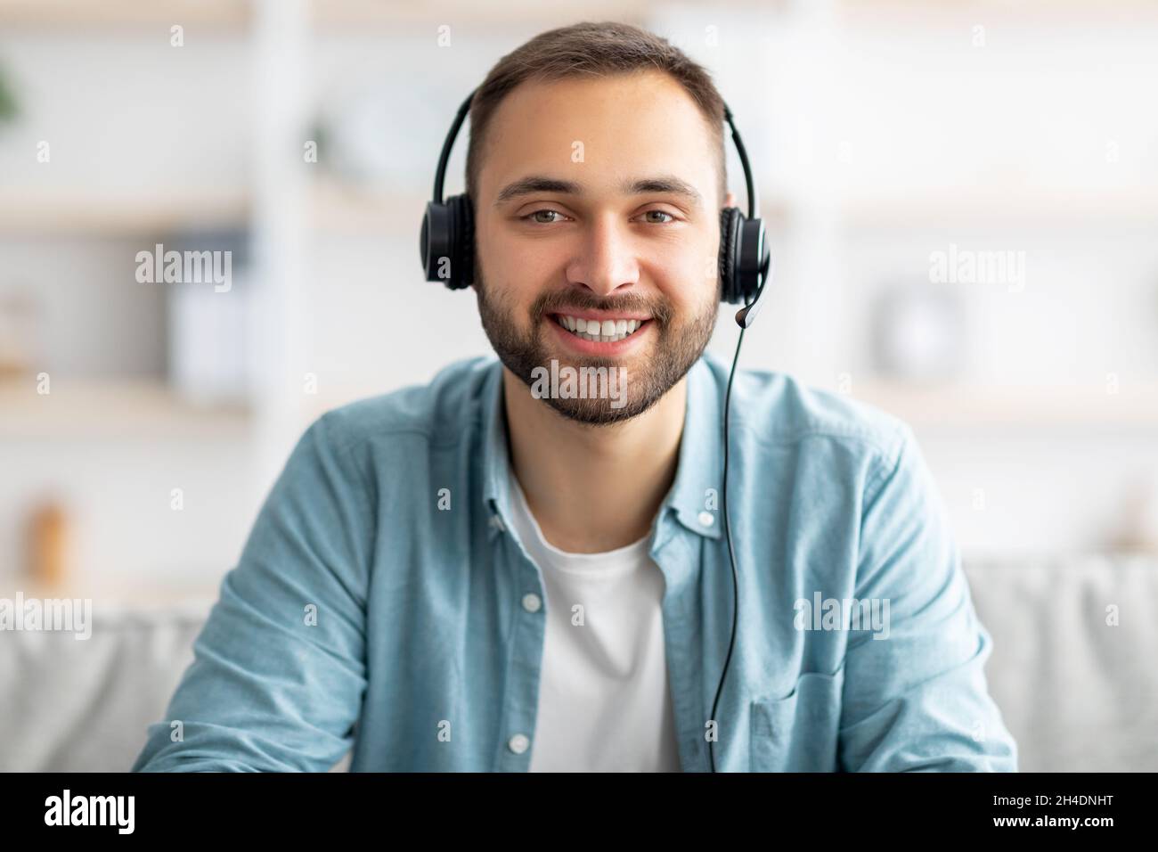 Allegro ragazzo caucasico giovane in cuffie che ha una videochiamata online, partecipare a una conferenza o a una riunione remota Foto Stock