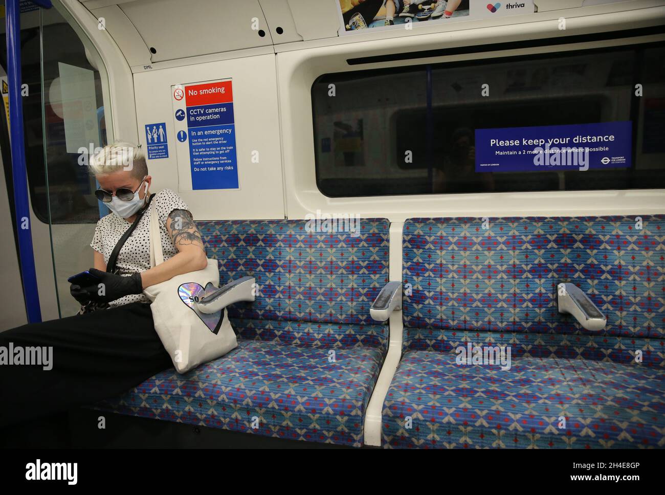Un pendolari che indossa una maschera facciale mantiene le distanze sociali mentre viaggia su un treno della metropolitana della linea Piccadilly a Londra, mentre il governo inizia ad allentare alcune misure di blocco in Inghilterra. Data foto: Lunedì 1 giugno 2020. Foto Stock