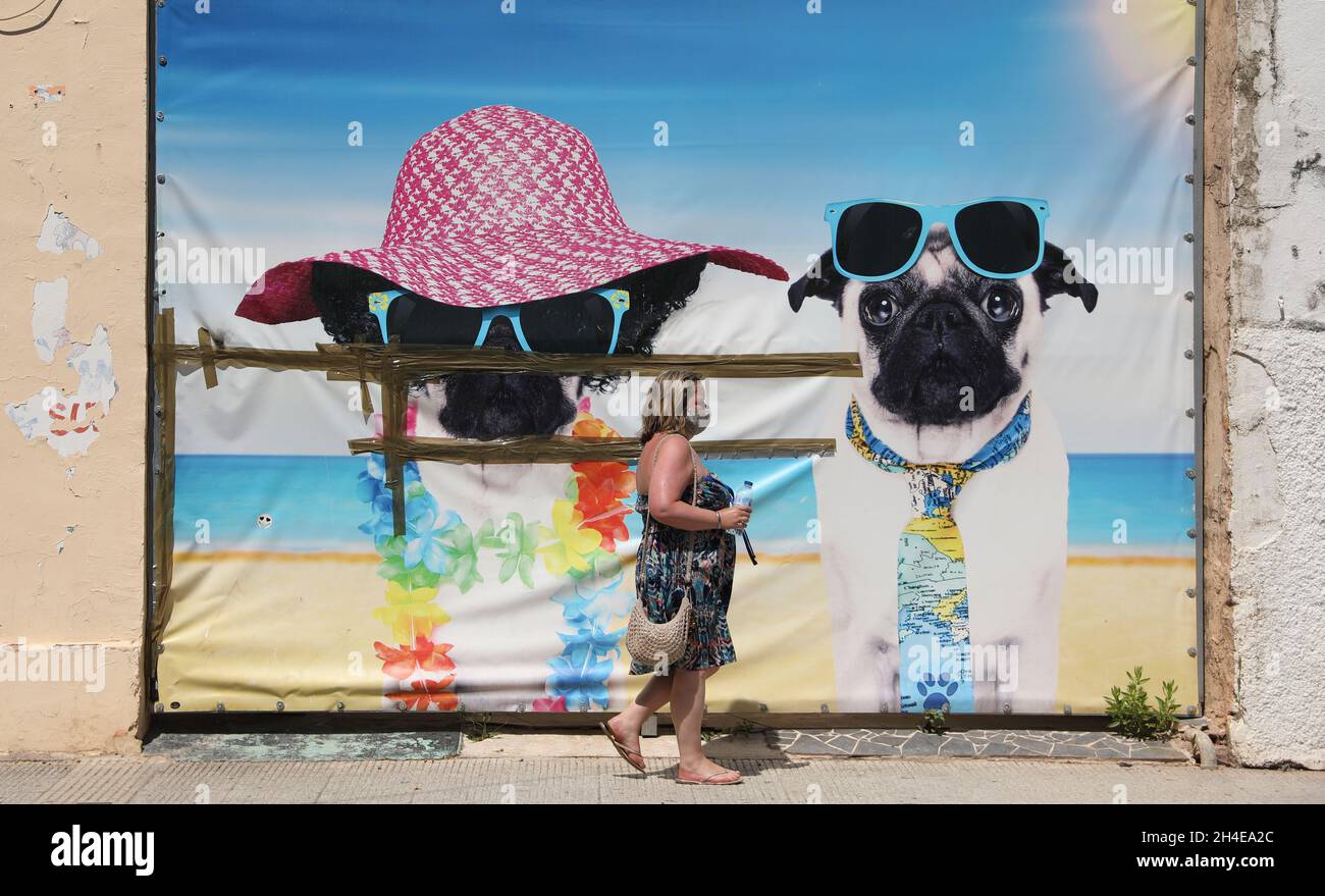 Un viso turistico che copre passeggiate accanto ad un'opera d'arte a tema spiaggia nel quartiere inglese di Levante a Benidorm, una località balneare sulla costa orientale della Spagna, Come l'industria del turismo in Spagna è stato colpito duramente dall'ultimo requisito di quarantena di 14 giorni da parte del governo britannico per tutti i turisti che viaggiano dalla Spagna a causa dei suoi alti livelli di casi COVID-19. Data foto: Venerdì 31 luglio 2020. Foto Stock