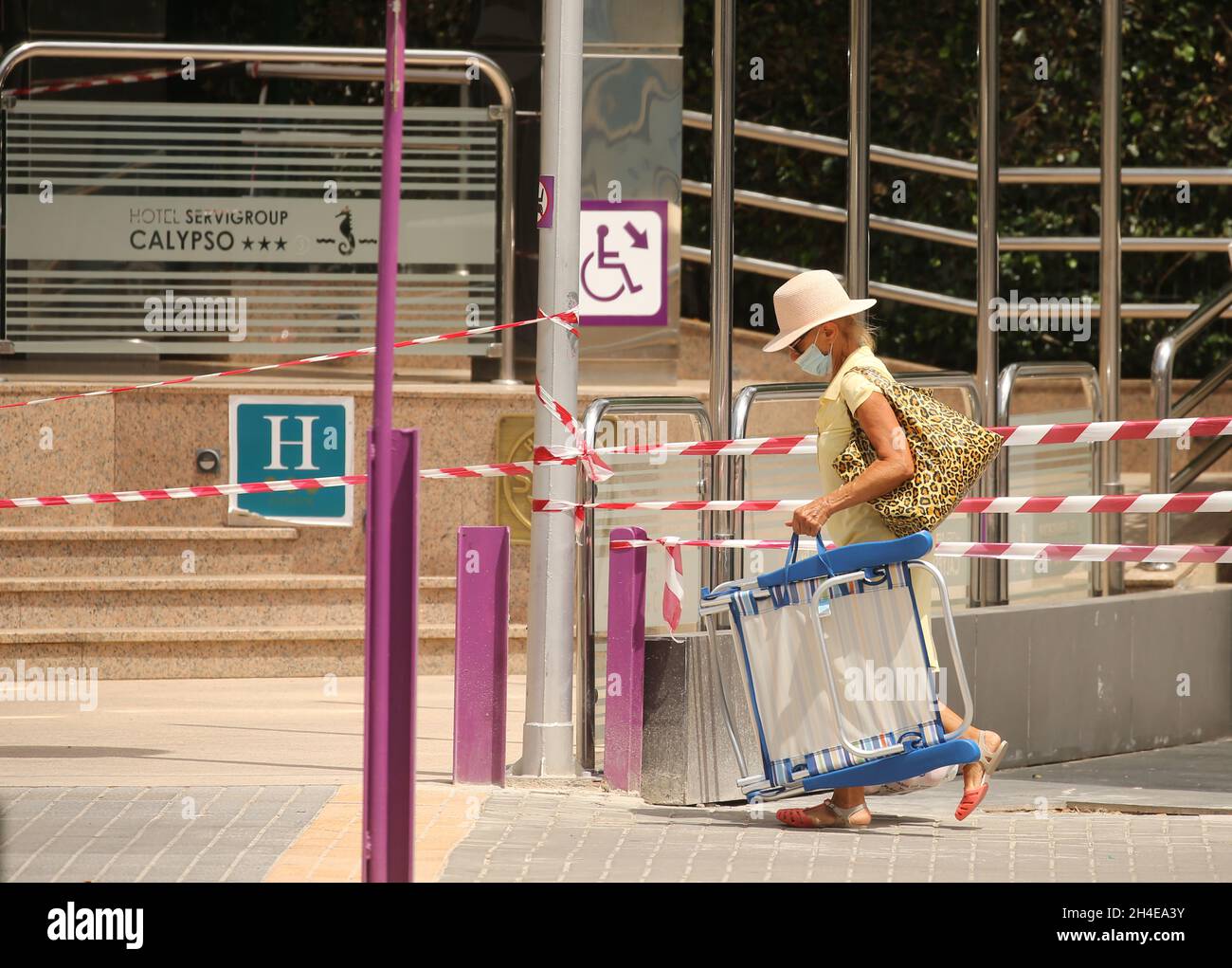 Un turista passa davanti ad un hotel chiuso nel distretto inglese di Levante a Benidorm, una località balneare sulla costa orientale della Spagna, che rimane quasi vuota a seguito della quarantena del governo britannico a tutti i turisti che viaggiano dalla Spagna a causa dei suoi alti livelli di casi COVID-19. Data foto: Giovedì 30 luglio 2020. Foto Stock