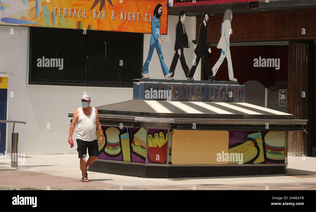 Un turista che indossa il viso che copre passeggiate attraverso un bar con terrazza chiusa nel quartiere inglese di Benidorm, una località balneare sulla costa orientale della Spagna, Dove l'industria del turismo è stata duramente colpita dall'ultimo requisito di quarantena di 14 giorni da parte del governo britannico per tutti i turisti che viaggiano dalla Spagna a causa dei suoi alti livelli di casi COVID-19. Data foto: Giovedì 30 luglio 2020. Foto Stock