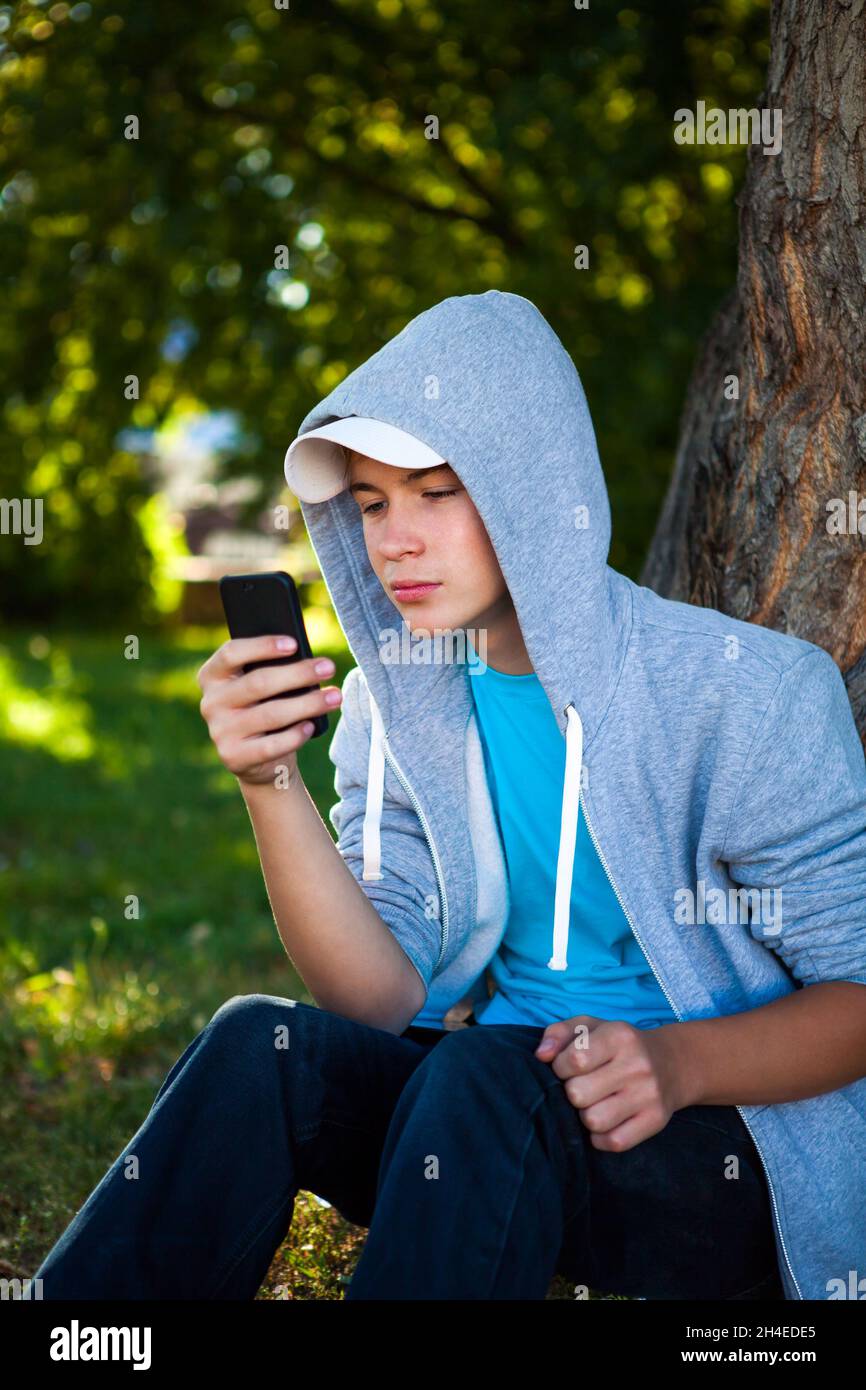Adolescente con cellulare sotto l'albero nel Parco Foto Stock