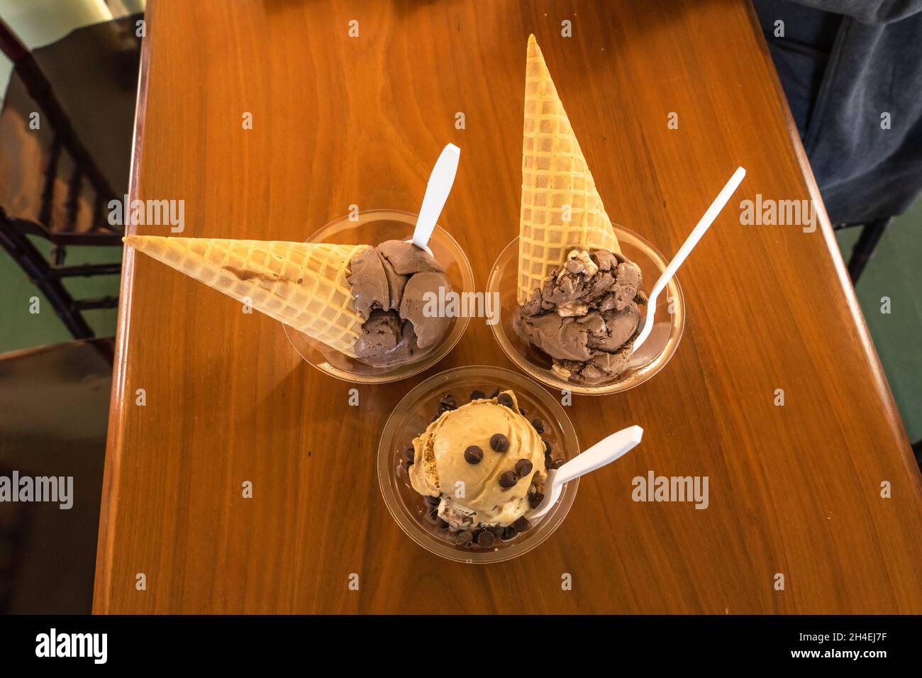 Saporiti coni gelato al cioccolato e tazze con cucchiai Foto Stock