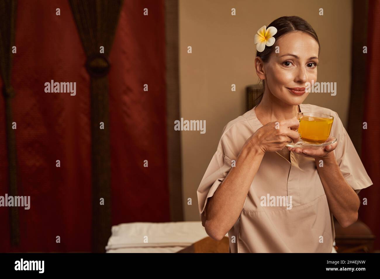 Cliente salone di bellezza calmo con bevanda a base di erbe in posa per la macchina fotografica Foto Stock