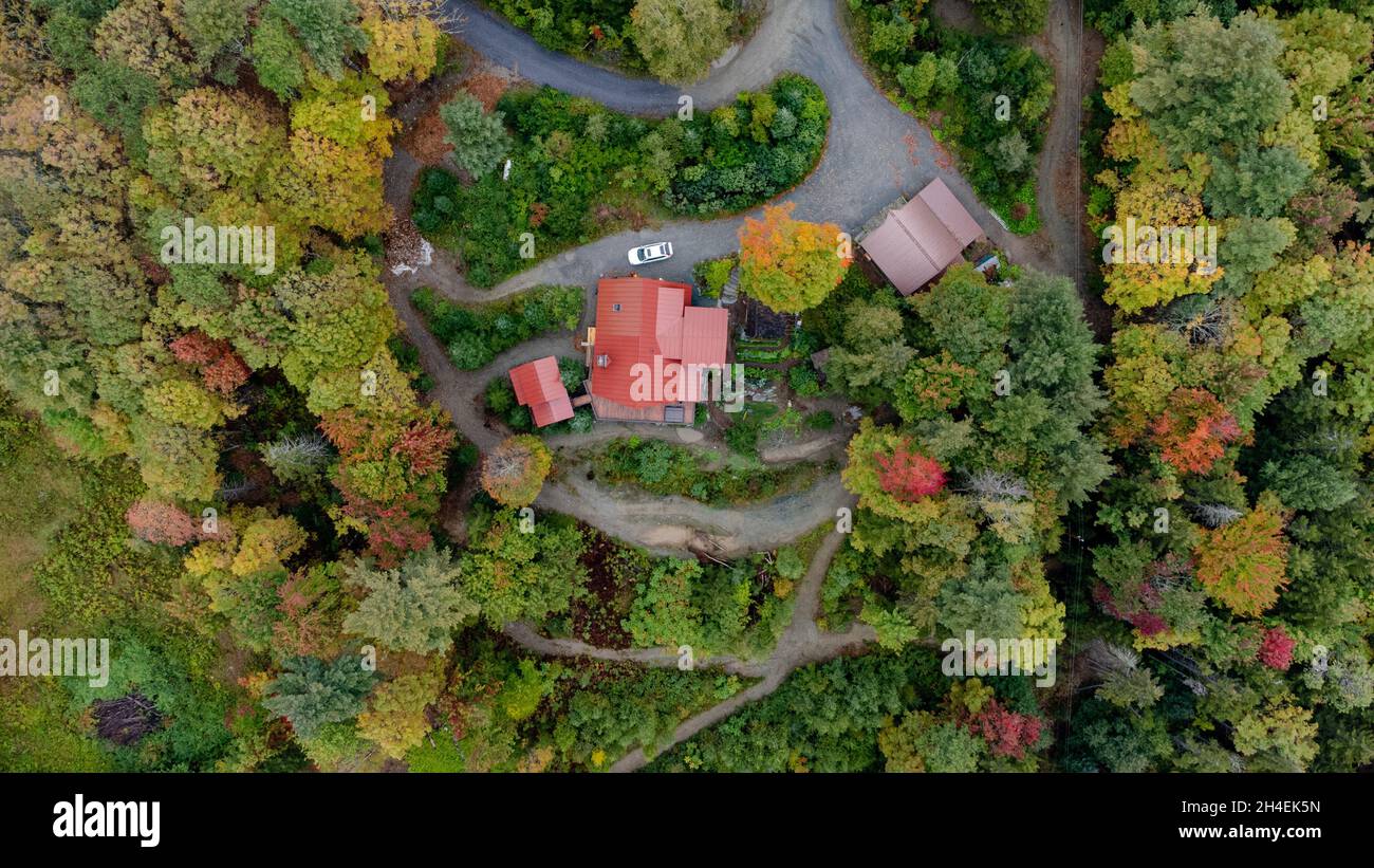 Vista aerea dall'alto della cabina del Vermont circondata da alberi colorati in autunno Foto Stock