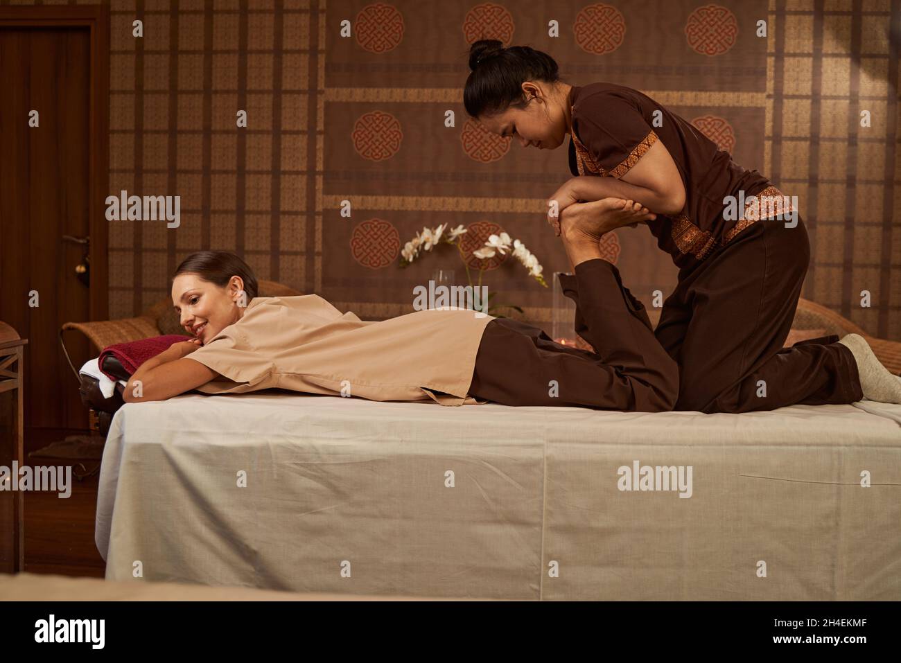 Massoterapista esperto che allunga i muscoli delle gambe del paziente Foto Stock