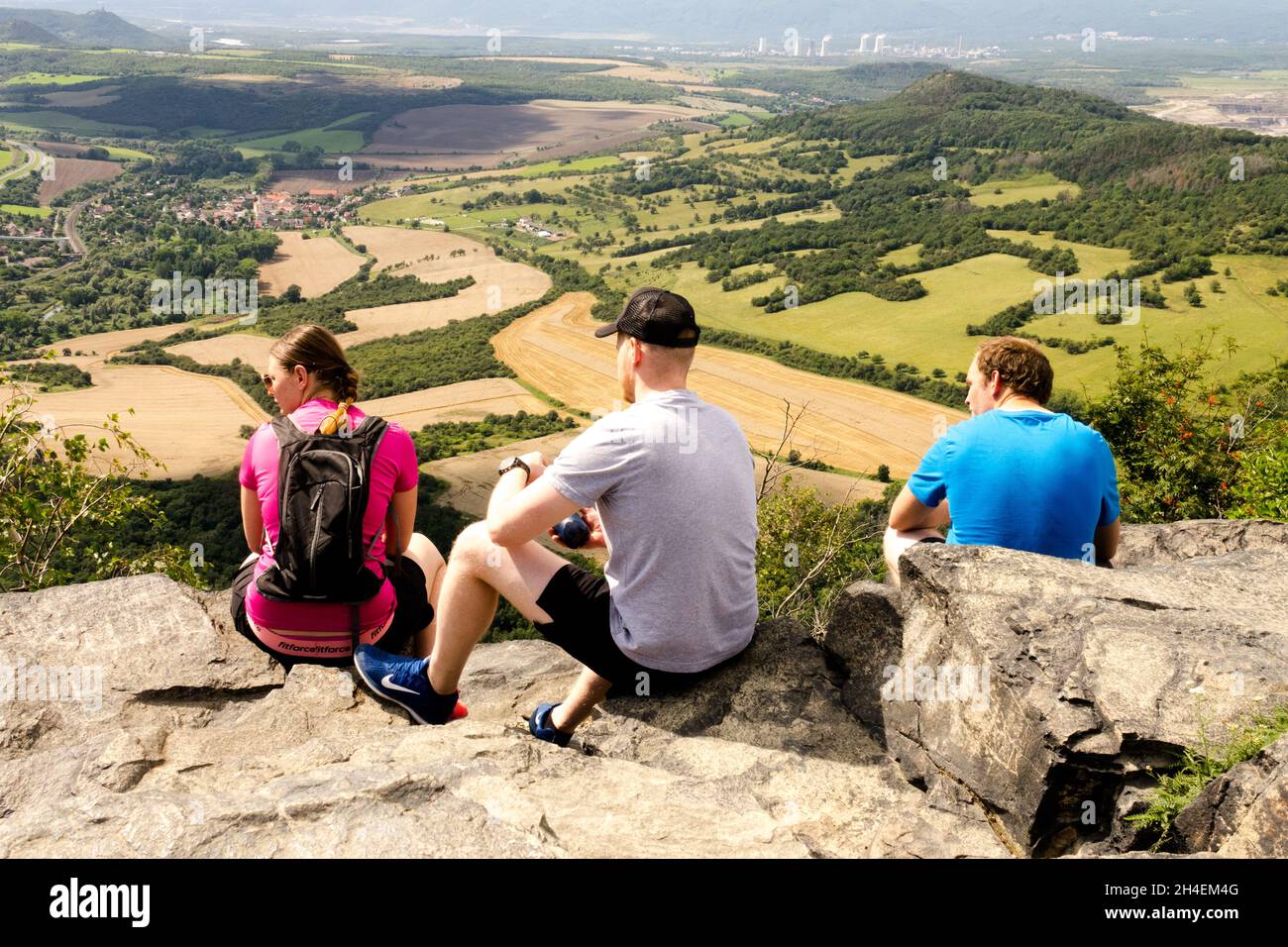 Escursionisti che riposano sulla cima della collina e che sbirciano nella valle del Monte Ceske Stredohori Repubblica Ceca, Europa Foto Stock