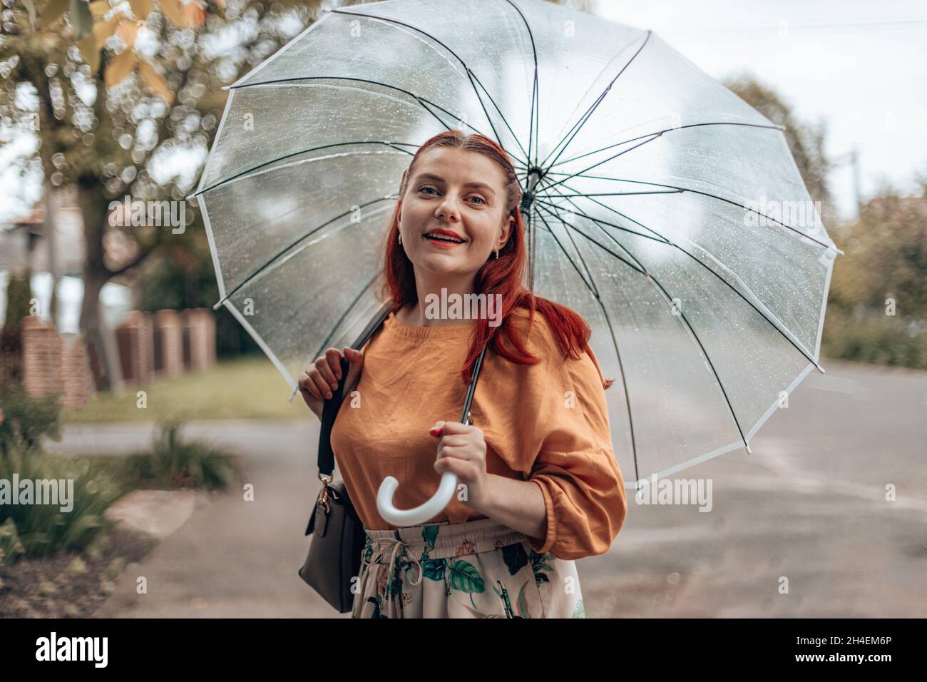 Giovane donna elegante in abiti luminosi sotto un ombrello trasparente in  caso di maltempo Foto stock - Alamy