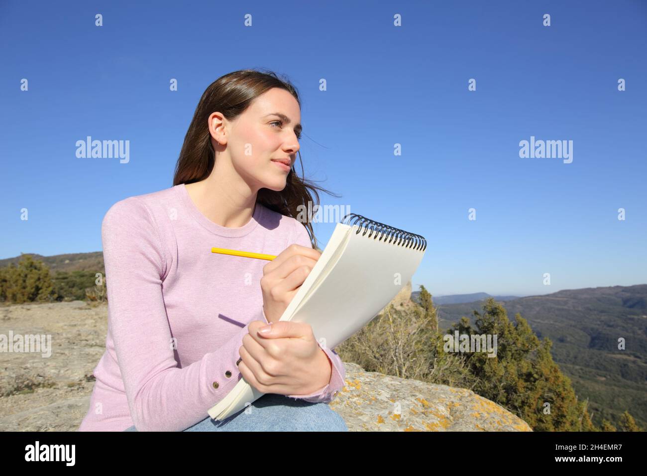 Donna felice che si disegna all'aperto sul taccuino in montagna Foto Stock