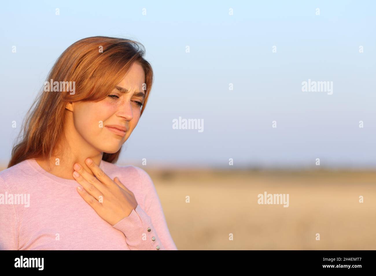 Donna stressata che soffre di mal di gola in un campo Foto Stock