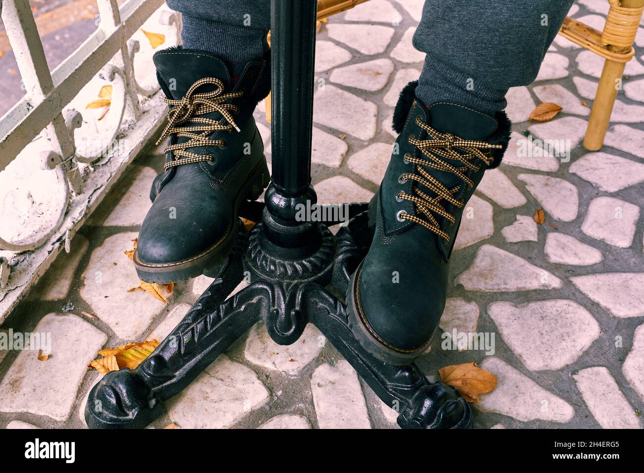 Gambe della donna sotto il tavolo nelle moderne scarpe invernali nere. Foto Stock